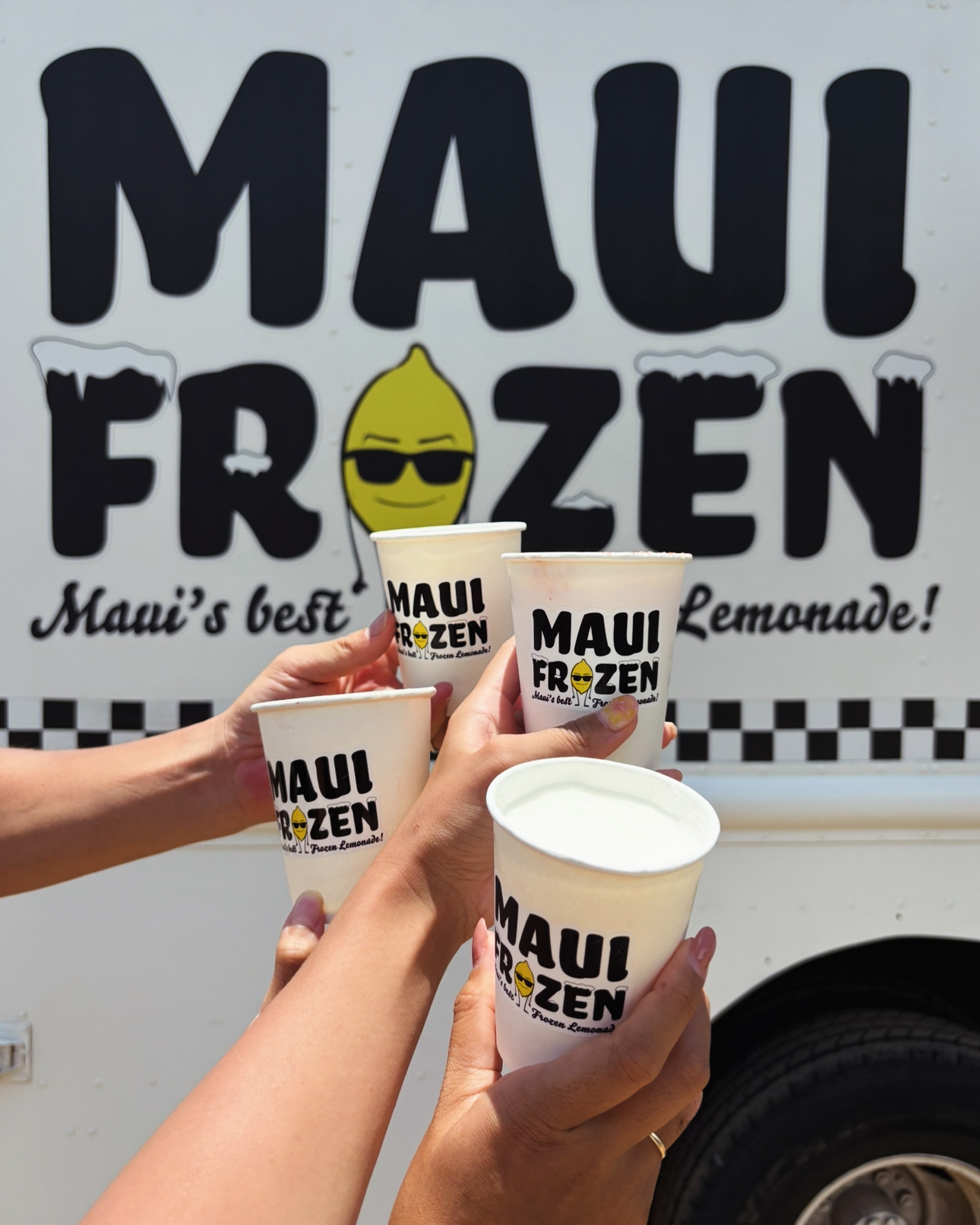 Two Maui Slush cups held up next to the Maui Frozen truck