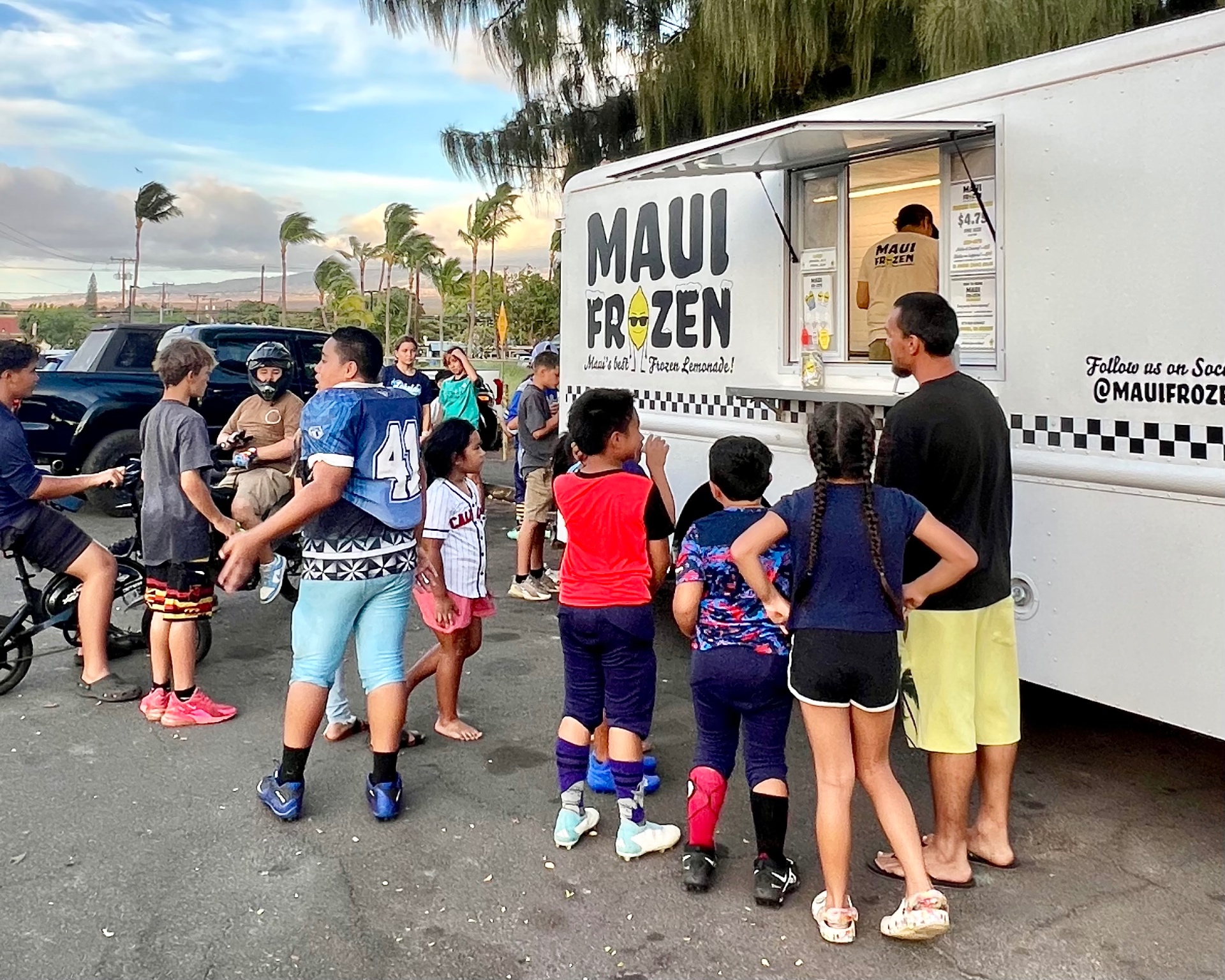 People in line at the Maui Frozen truck at sunset